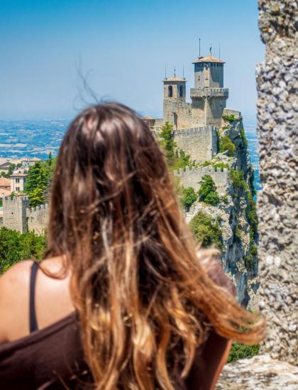 Donna osserva il castello di San Marino tra le mura antiche.