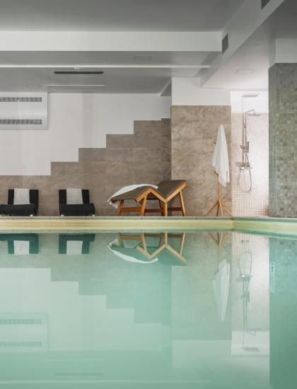 Piscina interna con lettini e doccia, ambiente rilassante.