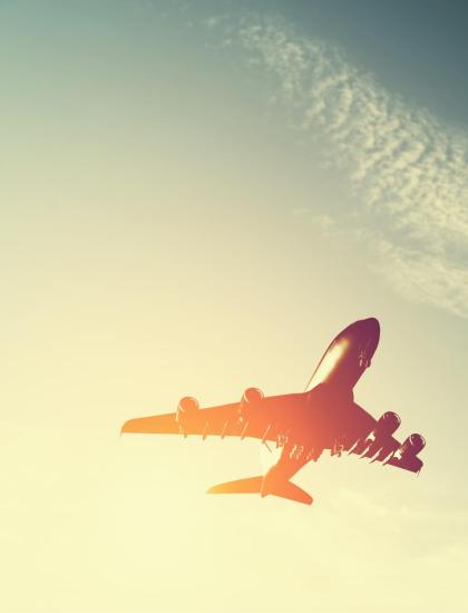 A plane soars high in the sunset sky, evoking freedom and adventure.