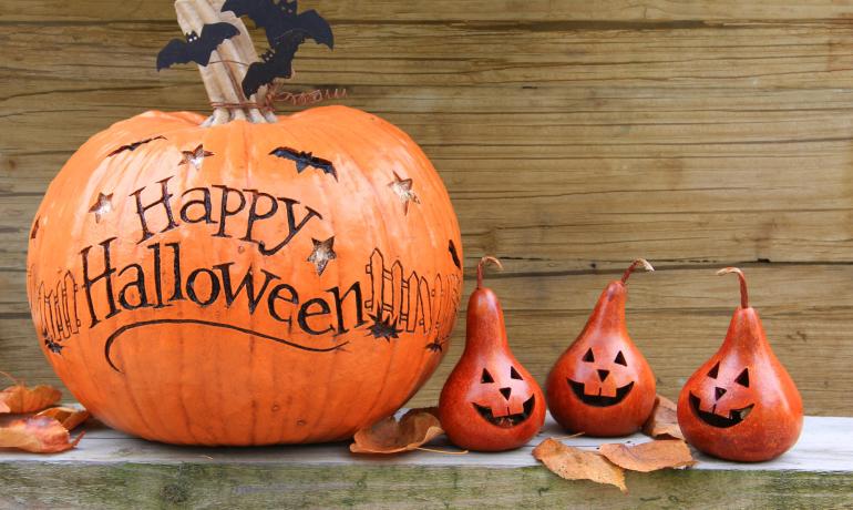 Citrouille sculptée avec chauves-souris et trois petites citrouilles pour Halloween.