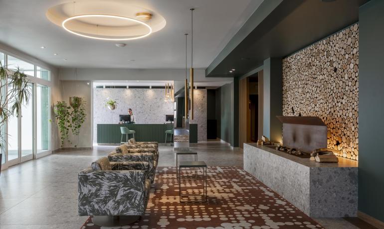 Elegante hall d'hotel con arredi moderni e dettagli naturali.