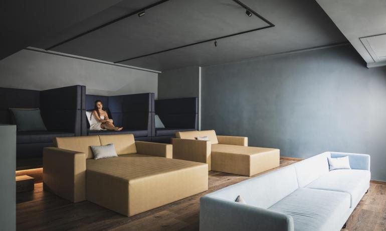 Salle de détente moderne avec canapés et une personne assise.