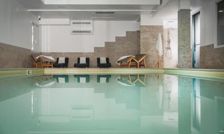 Piscina interna con lettini e doccia, ambiente rilassante.