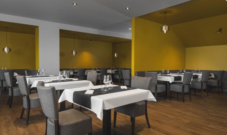 Modern restaurant with grey chairs and yellow walls.