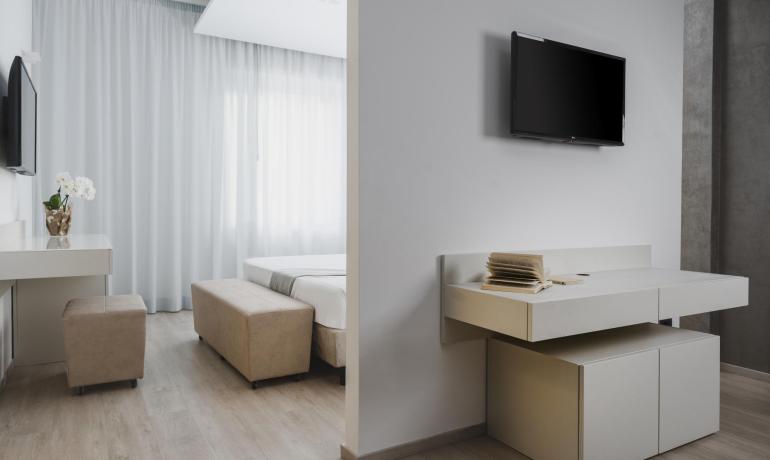 Chambre moderne avec TV, bureau, lit et décoration minimaliste.