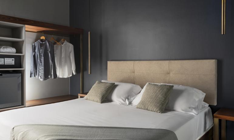 Camera moderna con letto matrimoniale e armadio aperto.