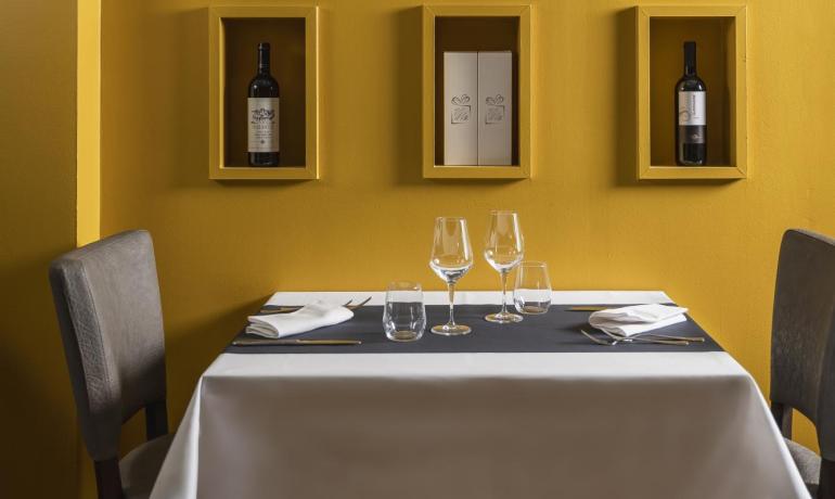 Elegant restaurant with yellow wall and shelves holding wine bottles.