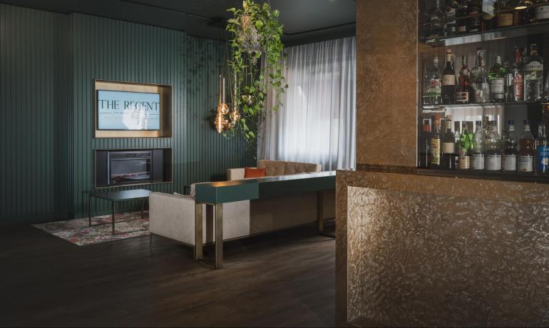 Elegant lounge bar with sofas, hanging plants, and liquor shelf.
