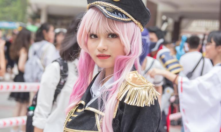Person in costume with pink hair at a crowded event.