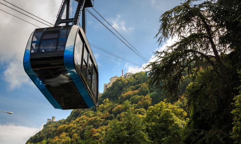 Funivia moderna attraversa un paesaggio montano verde e rigoglioso.