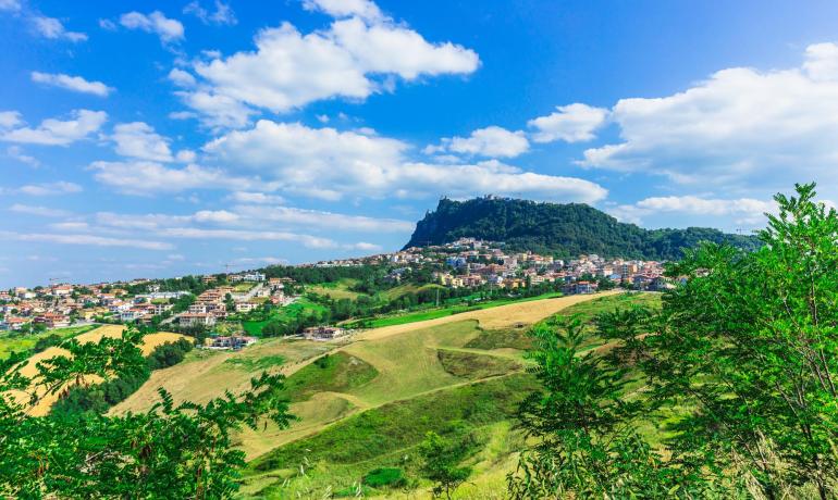 Paesaggio collinare con città e cielo blu.