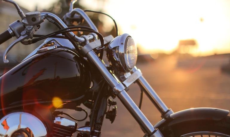 Motocicletta cromata al tramonto su strada aperta.
