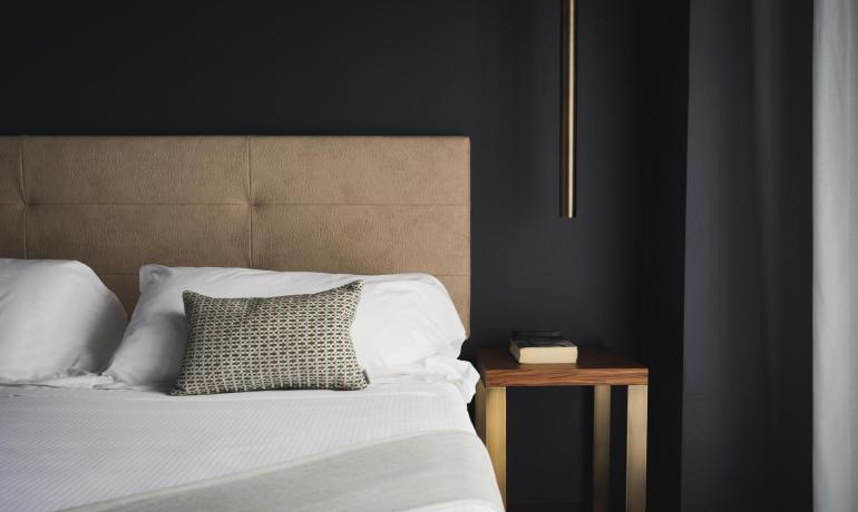 Camera moderna con letto, comodino e lampada.