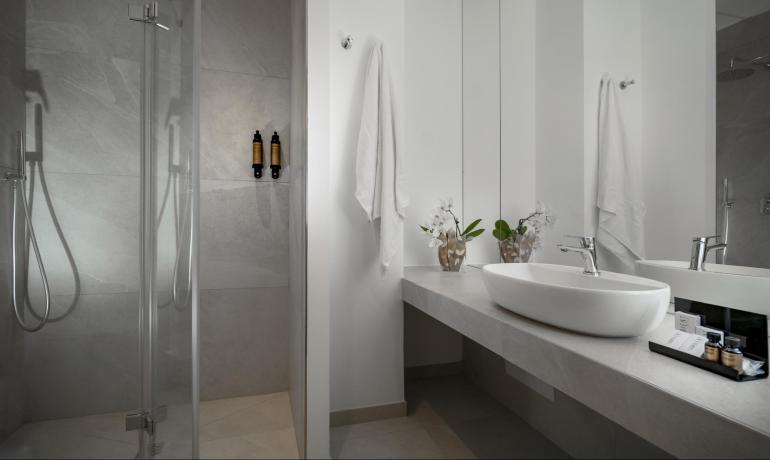 Bagno moderno con doccia, lavabo e specchio, decorato con fiori.