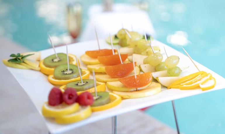 Frutta fresca su un piatto bianco vicino alla piscina.