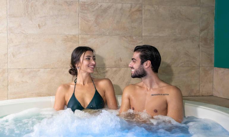 Lächelndes Paar im Whirlpool, intime und entspannte Atmosphäre.
