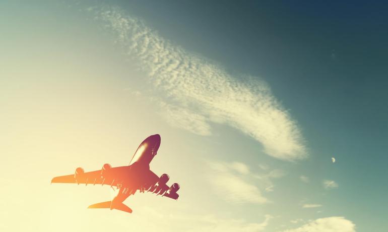 Ein Flugzeug fliegt hoch am Himmel bei Sonnenuntergang, Freiheit und Abenteuer erweckend.